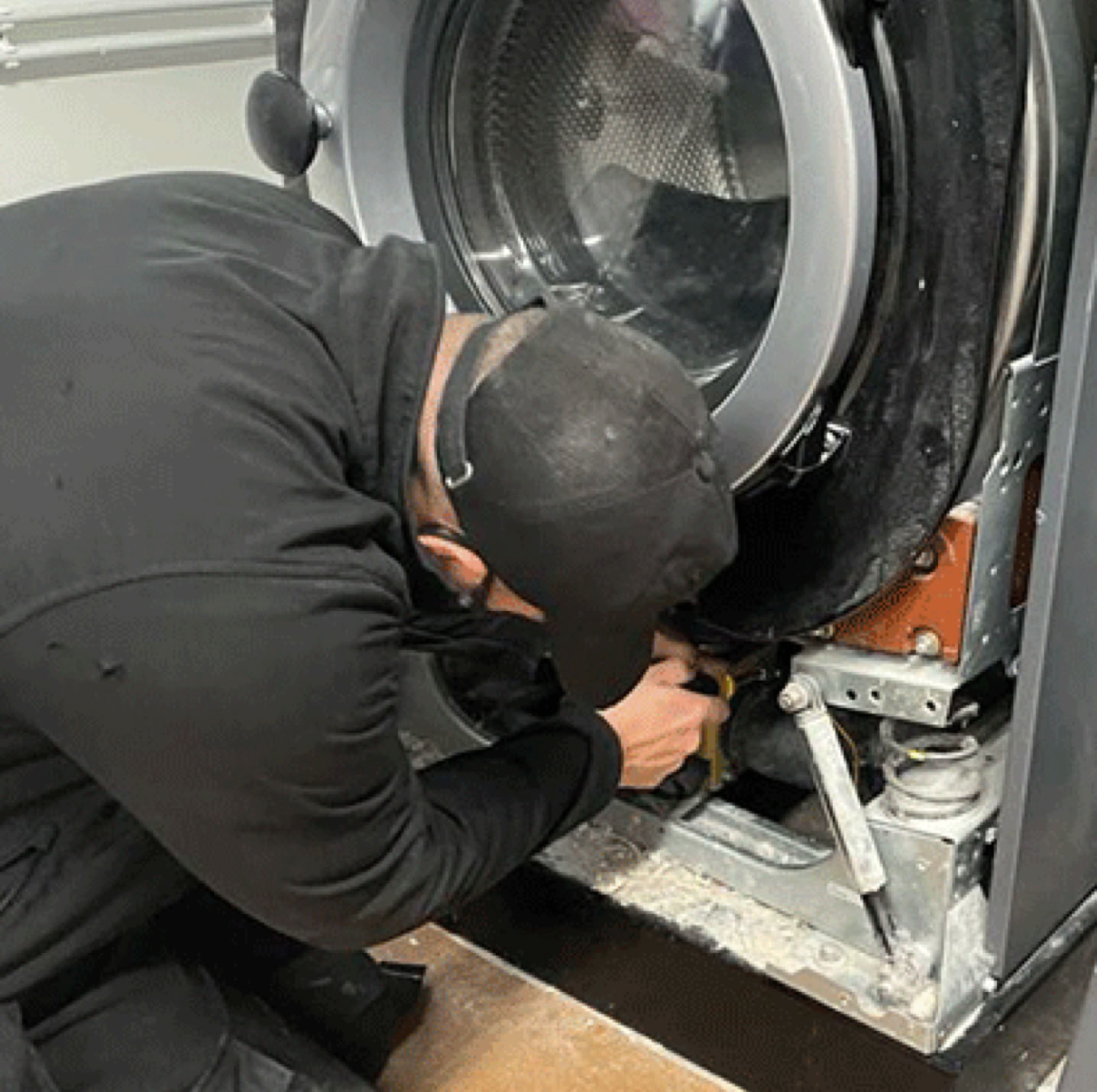 Two adults dancing in an industrial laundry with large machines and carts visible.
